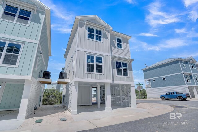 raised beach house with a carport, stairway, and board and batten siding