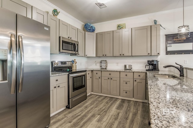 kitchen with appliances with stainless steel finishes, dark wood-type flooring, pendant lighting, crown molding, and sink