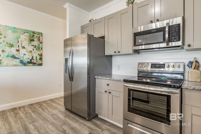 kitchen featuring light stone counters, crown molding, appliances with stainless steel finishes, and light hardwood / wood-style floors