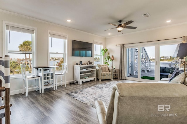 living room with a wealth of natural light, dark wood-type flooring, and crown molding