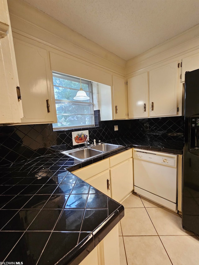 kitchen featuring white dishwasher, black fridge, white cabinetry, backsplash, and sink