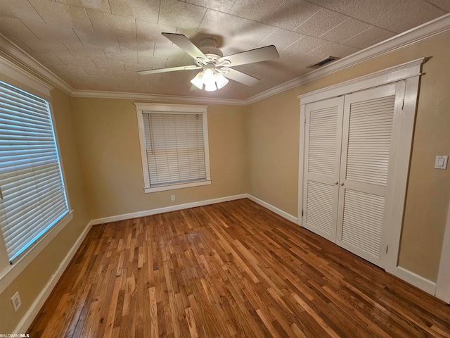 unfurnished bedroom featuring crown molding, a closet, ceiling fan, and dark hardwood / wood-style flooring