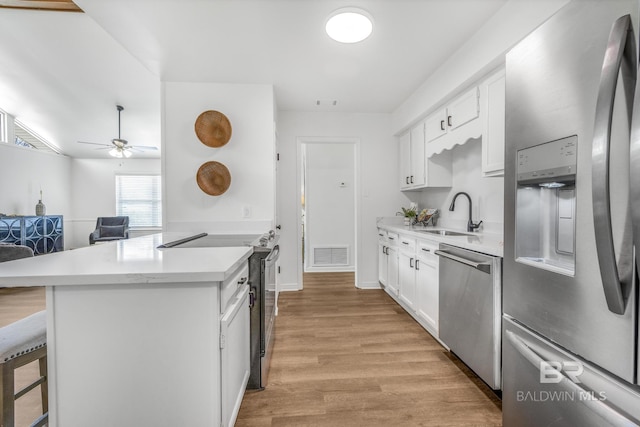 kitchen with visible vents, a breakfast bar, a sink, stainless steel appliances, and light countertops