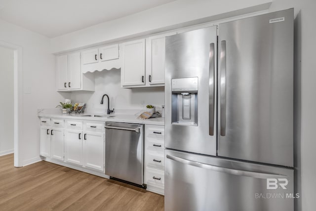 kitchen featuring a sink, light countertops, white cabinets, light wood-style floors, and appliances with stainless steel finishes