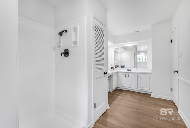 full bath featuring vanity, wood finished floors, visible vents, baseboards, and a shower