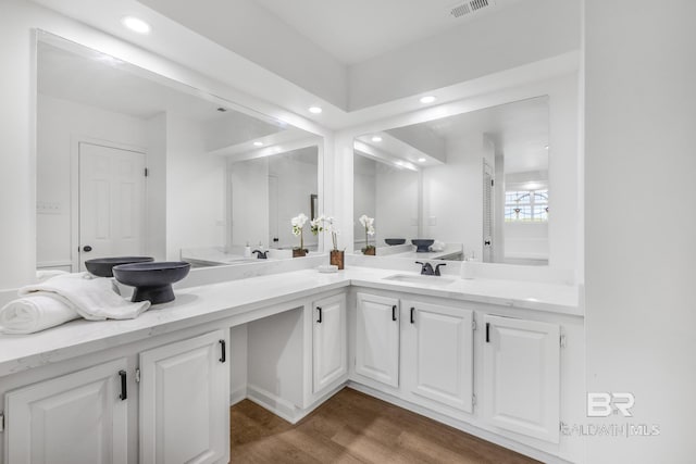 full bathroom featuring visible vents, double vanity, recessed lighting, wood finished floors, and a sink