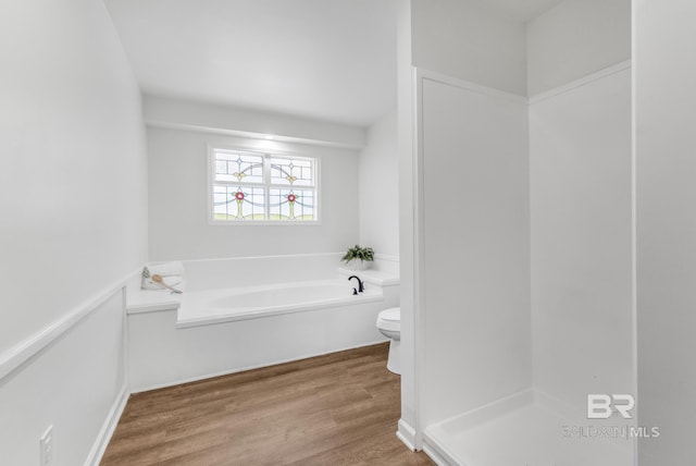 bathroom featuring a garden tub, wood finished floors, and toilet