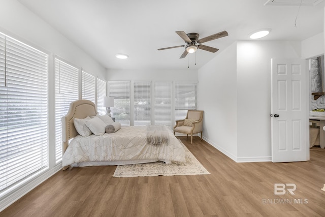 bedroom with attic access, light wood-type flooring, baseboards, and a ceiling fan