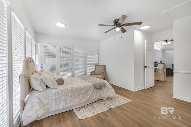 bedroom with ceiling fan, baseboards, attic access, and wood finished floors