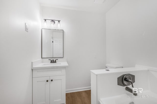 bathroom featuring vanity, a tub, wood finished floors, and baseboards