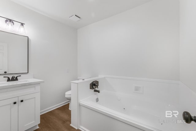 full bathroom featuring baseboards, toilet, a whirlpool tub, wood finished floors, and vanity