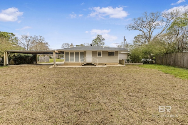 view of front of house with a carport, a chimney, a front yard, and fence