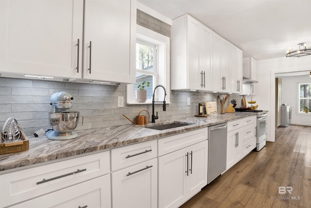 kitchen with light stone counters, white gas stove, stainless steel dishwasher, white cabinetry, and a sink