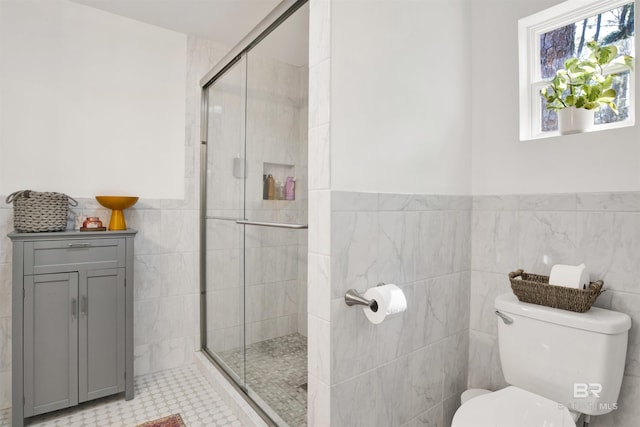 full bath with toilet, a stall shower, tile walls, and wainscoting