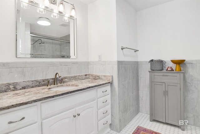 full bath featuring a wainscoted wall, a shower stall, vanity, and tile walls