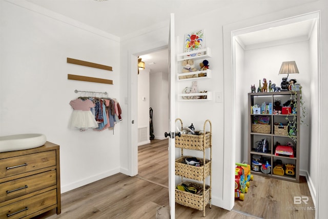 interior space with light wood-style flooring, visible vents, baseboards, and ornamental molding