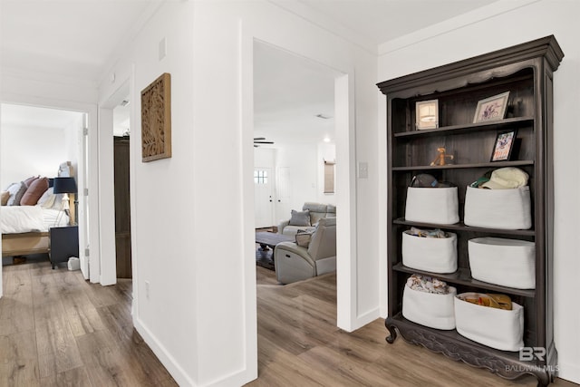 hallway with ornamental molding, baseboards, and wood finished floors