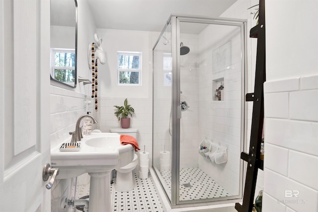 bathroom with a wainscoted wall, a shower stall, and tile walls