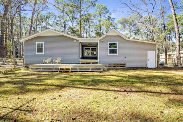 rear view of house with a deck, a lawn, and fence