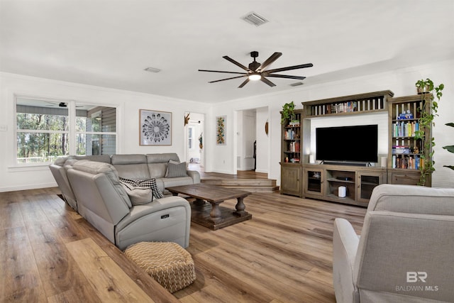 living room featuring baseboards, ceiling fan, visible vents, and wood finished floors