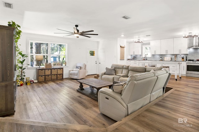 living room with visible vents, ceiling fan, and light wood-style flooring