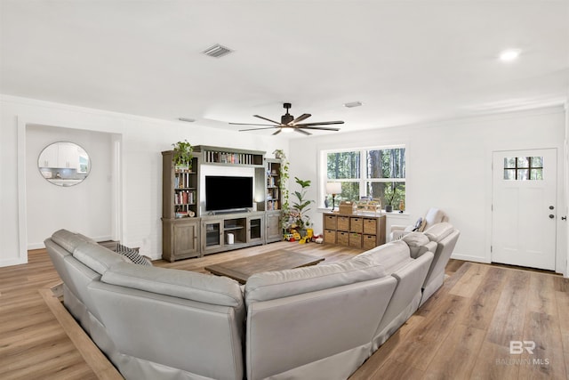 living area featuring visible vents, ceiling fan, baseboards, and wood finished floors