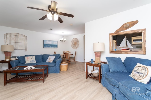 living area featuring visible vents, baseboards, wood finished floors, and ceiling fan with notable chandelier