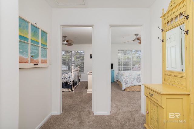 hall featuring a wealth of natural light, baseboards, and light colored carpet