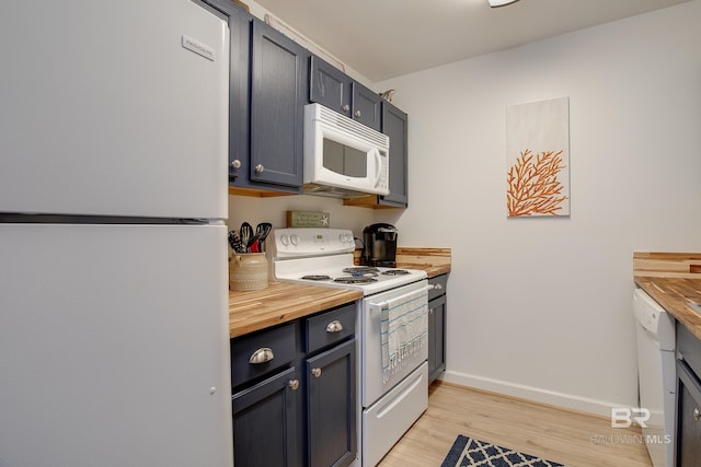 kitchen featuring wooden counters, light wood finished floors, white appliances, and baseboards