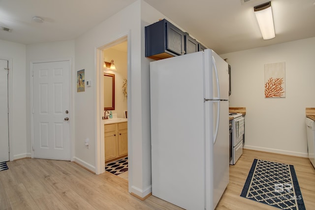 kitchen featuring white appliances, light wood-style floors, baseboards, and a sink