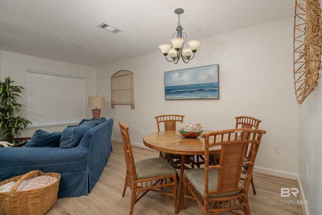 dining area featuring a chandelier, visible vents, light wood-style flooring, and baseboards