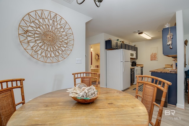 dining area with light wood-style floors and visible vents