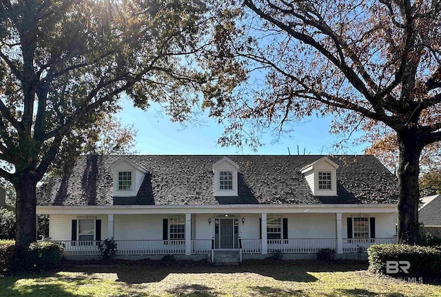 cape cod house featuring a front lawn and covered porch