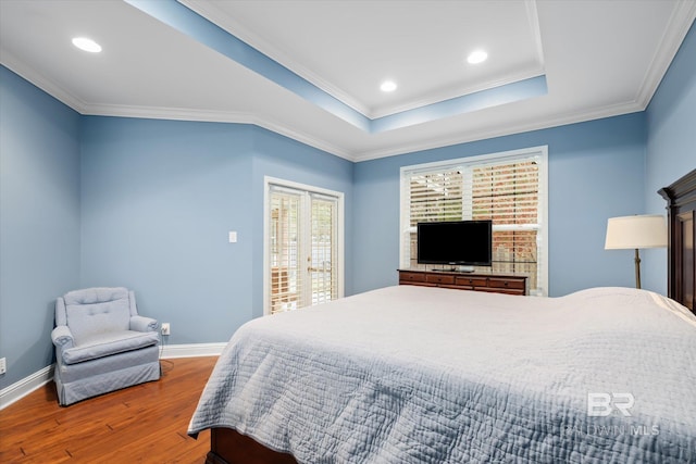 bedroom featuring crown molding, hardwood / wood-style flooring, and a raised ceiling