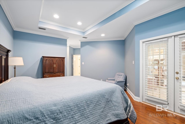 bedroom featuring crown molding, a tray ceiling, hardwood / wood-style floors, and access to outside