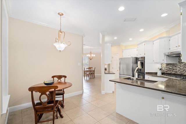 kitchen with appliances with stainless steel finishes, pendant lighting, white cabinetry, sink, and backsplash