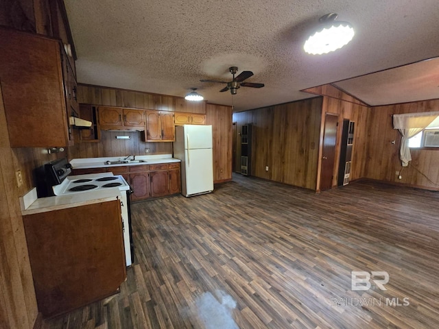 kitchen featuring dark wood finished floors, wood walls, white appliances, ceiling fan, and light countertops