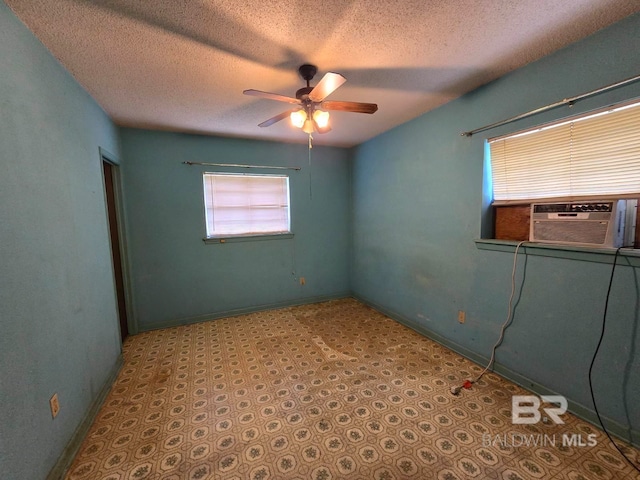 empty room featuring baseboards, a textured ceiling, cooling unit, and ceiling fan