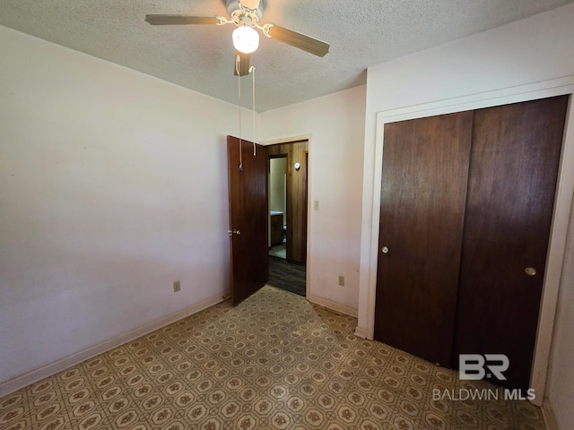 unfurnished bedroom featuring baseboards, a textured ceiling, a closet, and ceiling fan