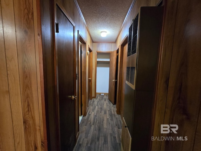 corridor featuring dark wood-type flooring, a textured ceiling, ornamental molding, and a heating unit