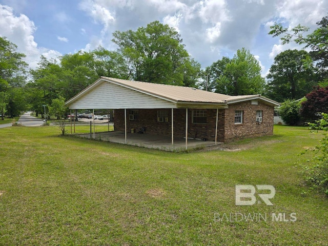 rear view of house featuring brick siding, a carport, and a yard