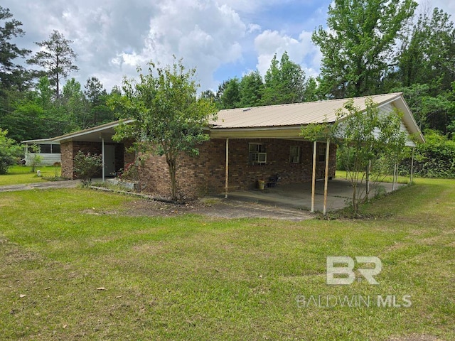 rear view of property featuring a carport, brick siding, a yard, and metal roof