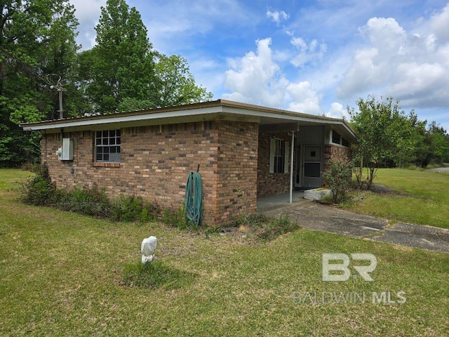 view of side of home with brick siding and a yard