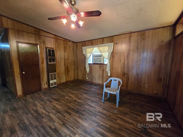 interior space featuring dark wood finished floors, a textured ceiling, wood walls, and baseboards
