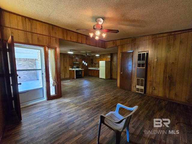 interior space with dark wood-style flooring, a textured ceiling, wood walls, and a ceiling fan
