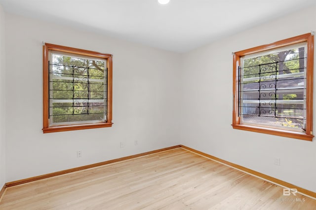 spare room featuring wood finished floors, a wealth of natural light, and baseboards