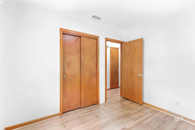 unfurnished bedroom featuring a closet, light wood-type flooring, visible vents, and baseboards