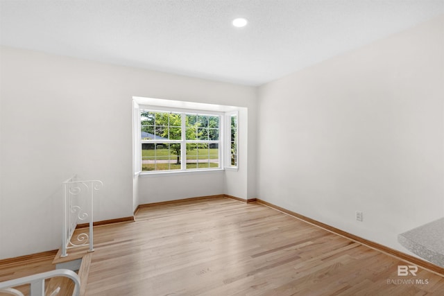 spare room with light wood-type flooring, baseboards, and recessed lighting