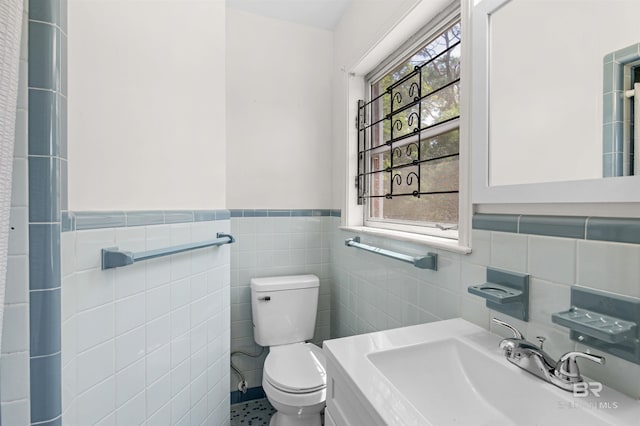 bathroom featuring plenty of natural light, toilet, a sink, and tile walls