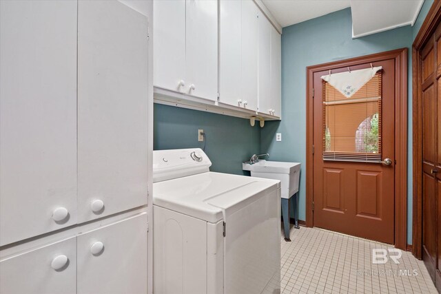 clothes washing area with washer / clothes dryer, cabinets, and light tile patterned floors